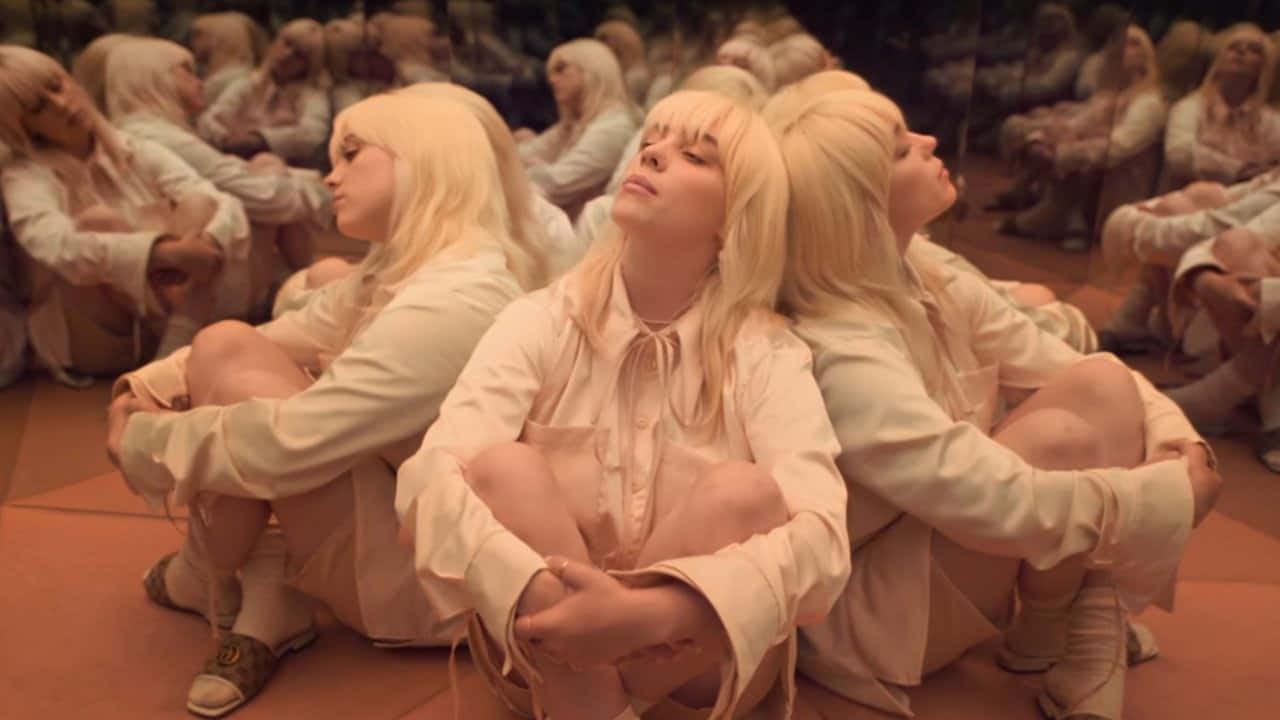 Blonde figures in cream clothing repeat around a warm mirrored room.