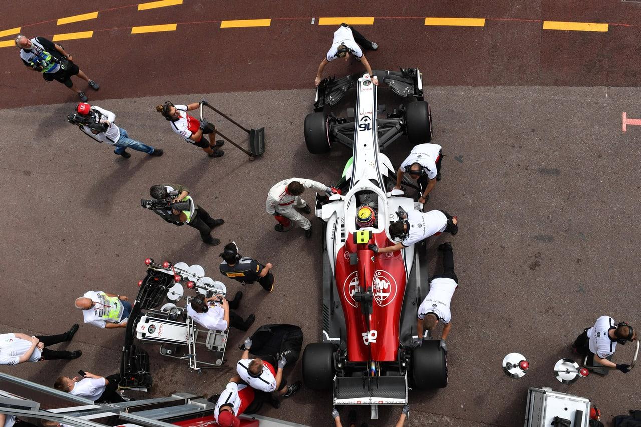 An overhead photograph shows Leclerc's historical white and red Sauber surrounded by crew. People, equipment and pit-lane markings remain around the central car.