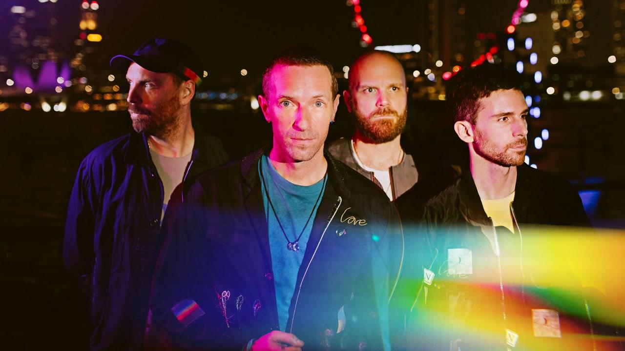 The four band members stand before blurred city lights as colored streaks cross the foreground. A dark skyline holds the scene together. Source: 4kwallpapers.com. Original artist not identified by the source page.