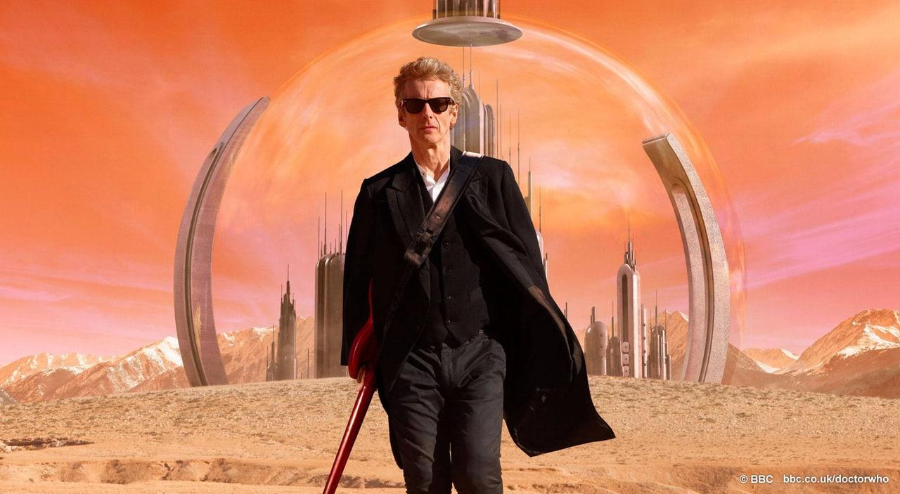The Twelfth Doctor walks before a domed city beneath an orange sky. Sand and distant mountains extend into both outer strips, with the BBC credit preserved.