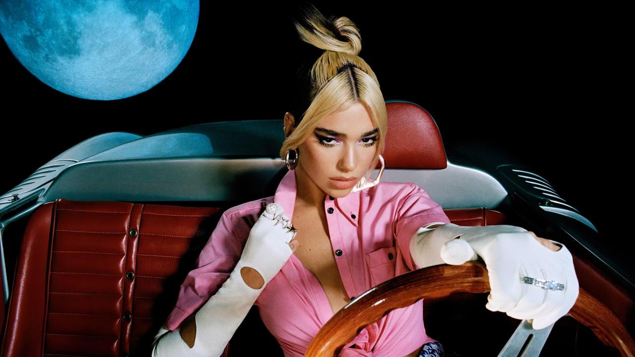 Dua Lipa sits behind a wooden steering wheel in a red-seat convertible under a blue moon. Upholstery and the curved car body fill the side areas. Source: 4kwallpapers.com. Original artist not identified by the source page.