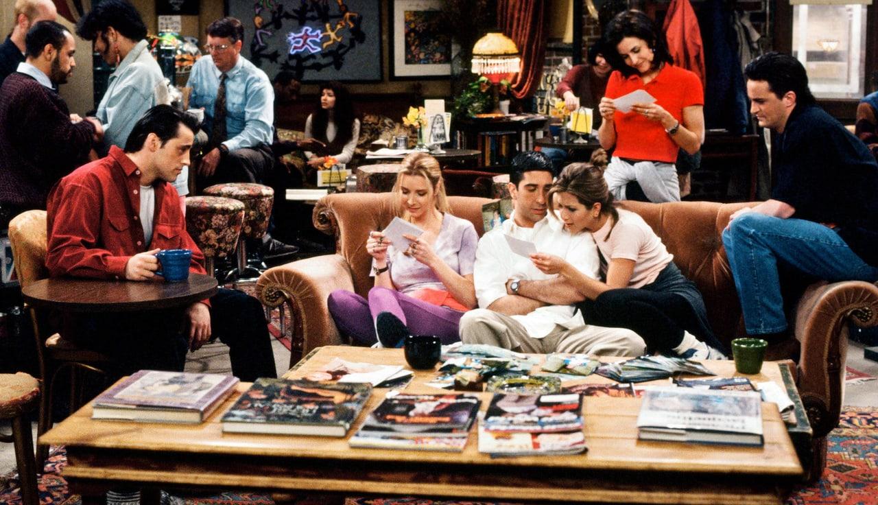 The friends gather around the familiar sofa and crowded coffee tables. Patrons, cups, lamps and seated cast members fill the whole cafe scene.