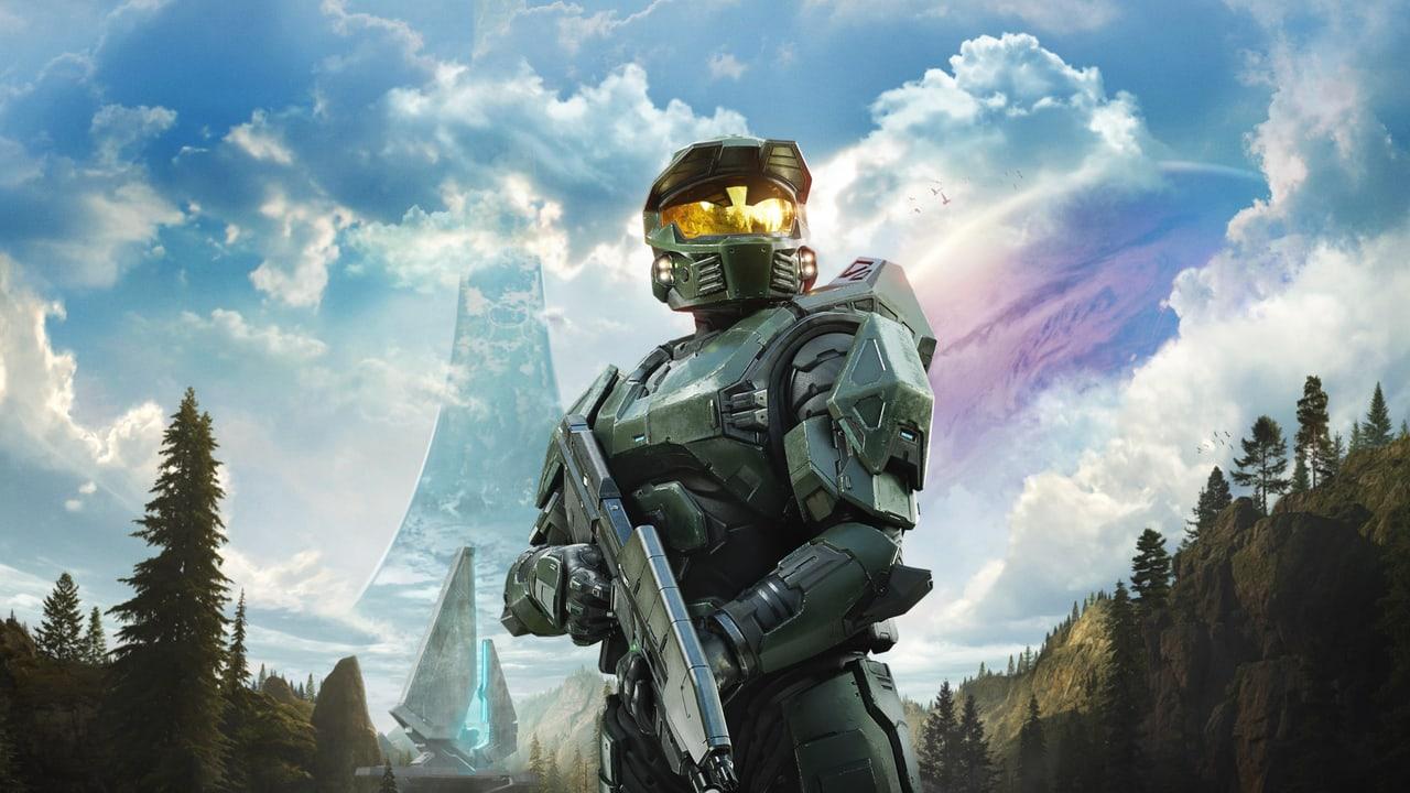 Master Chief stands before a mountain forest beneath a bright sky and an enormous ring. Pine trees and distant peaks frame the armor. Source: 4kwallpapers.com. Original artist not identified by the source page.
