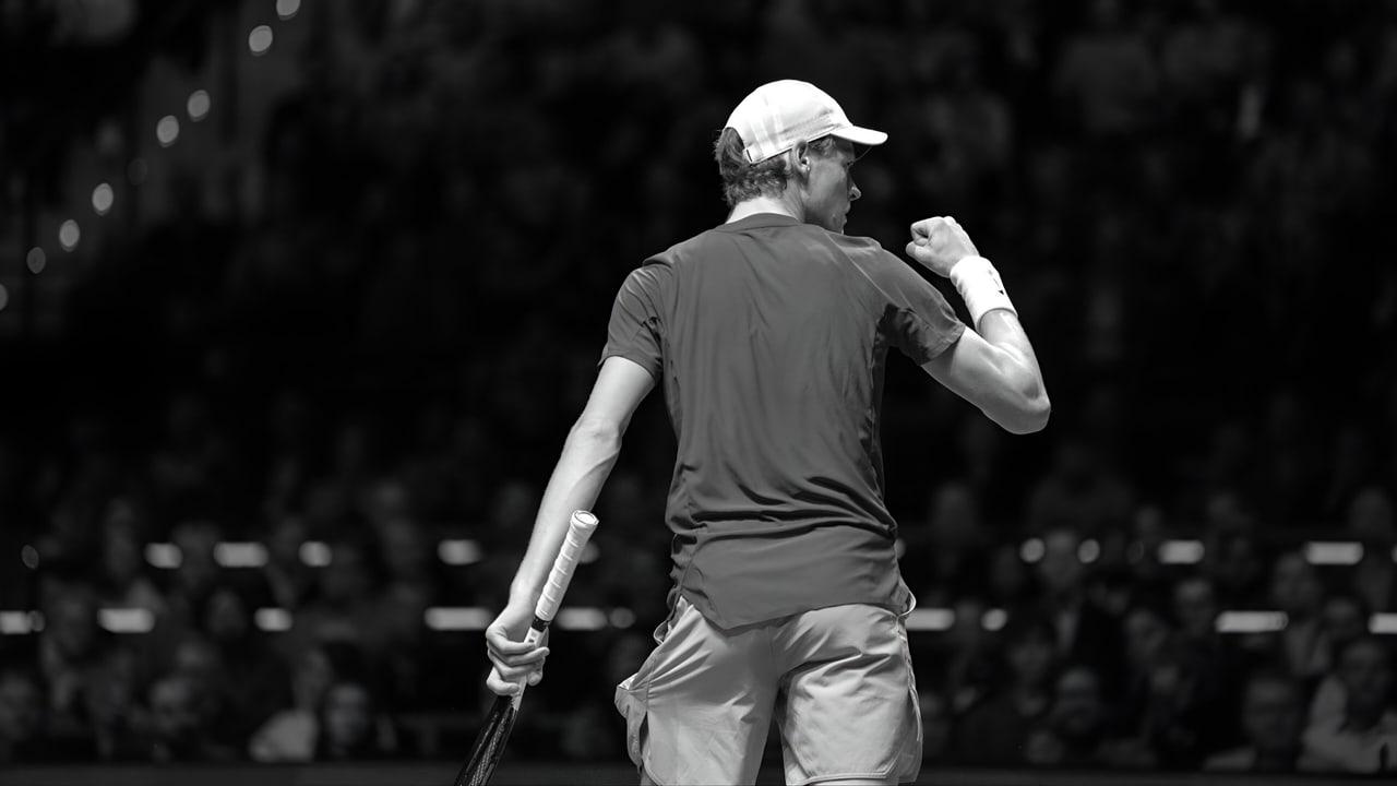 Sinner turns away with a raised fist in a black-and-white arena photograph. Rows of dark seats and soft lights surround the gesture. Source: m.gettywallpapers.com. Original artist not identified by the source page.