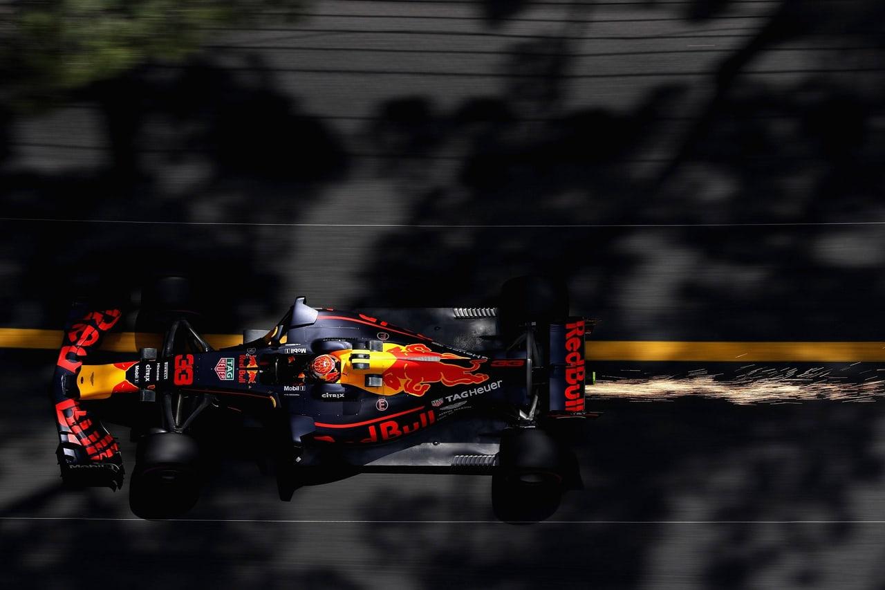 Max Verstappen’s number-33 Red Bull Formula One car cuts across a dark Monaco track in an overhead view with sparks trailing right.