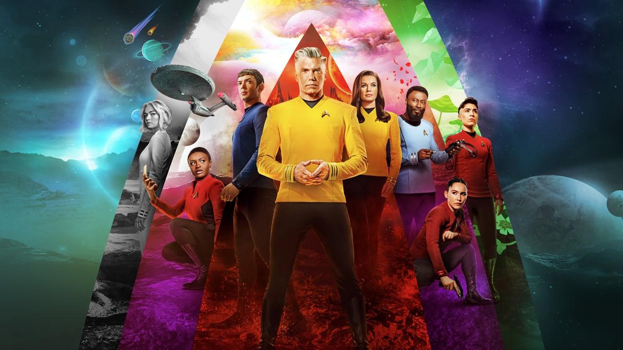 The crew gathers inside a bright triangular spectrum over a cosmic landscape. Nebula light, planets and dark terrain extend to both sides of the poster.