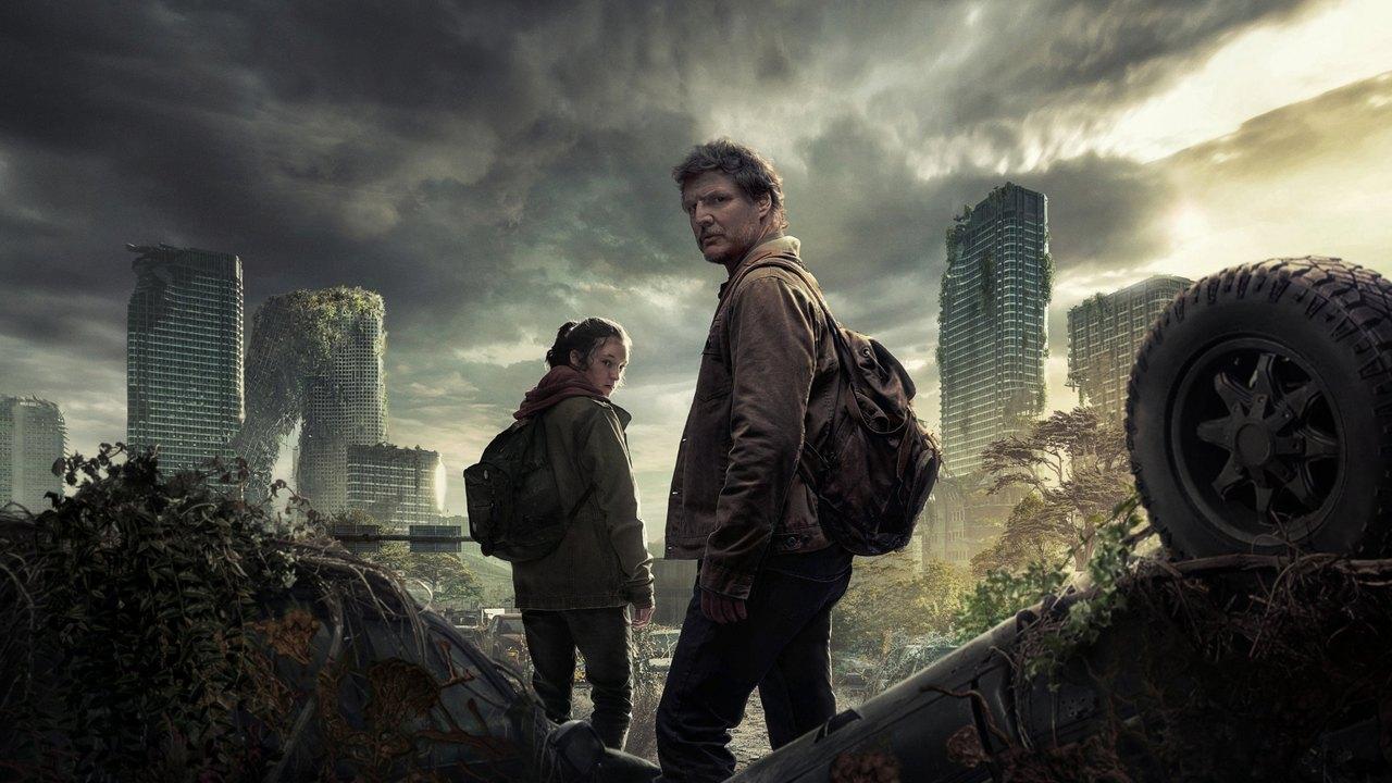 Joel and Ellie stand among abandoned vehicles, overgrown streets and damaged urban buildings.