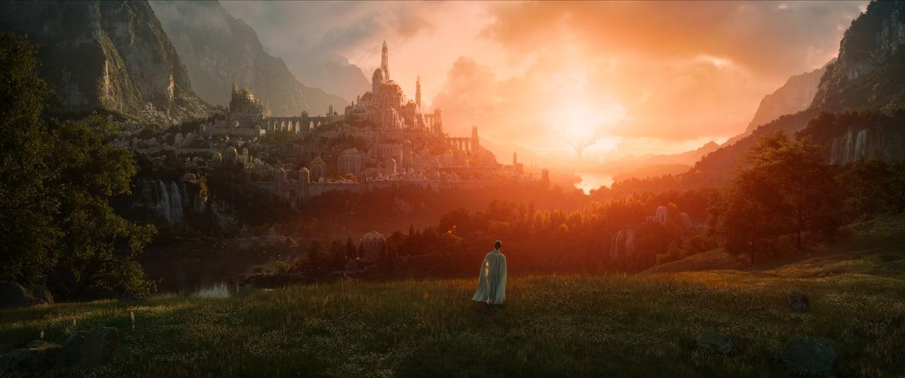 An elven city lies between steep mountains as orange light fills the valley. Terraces, trees and distant waterfalls remain visible beyond the lone foreground figure. Source: 4kwallpapers.com. Original artist not identified by the source page.