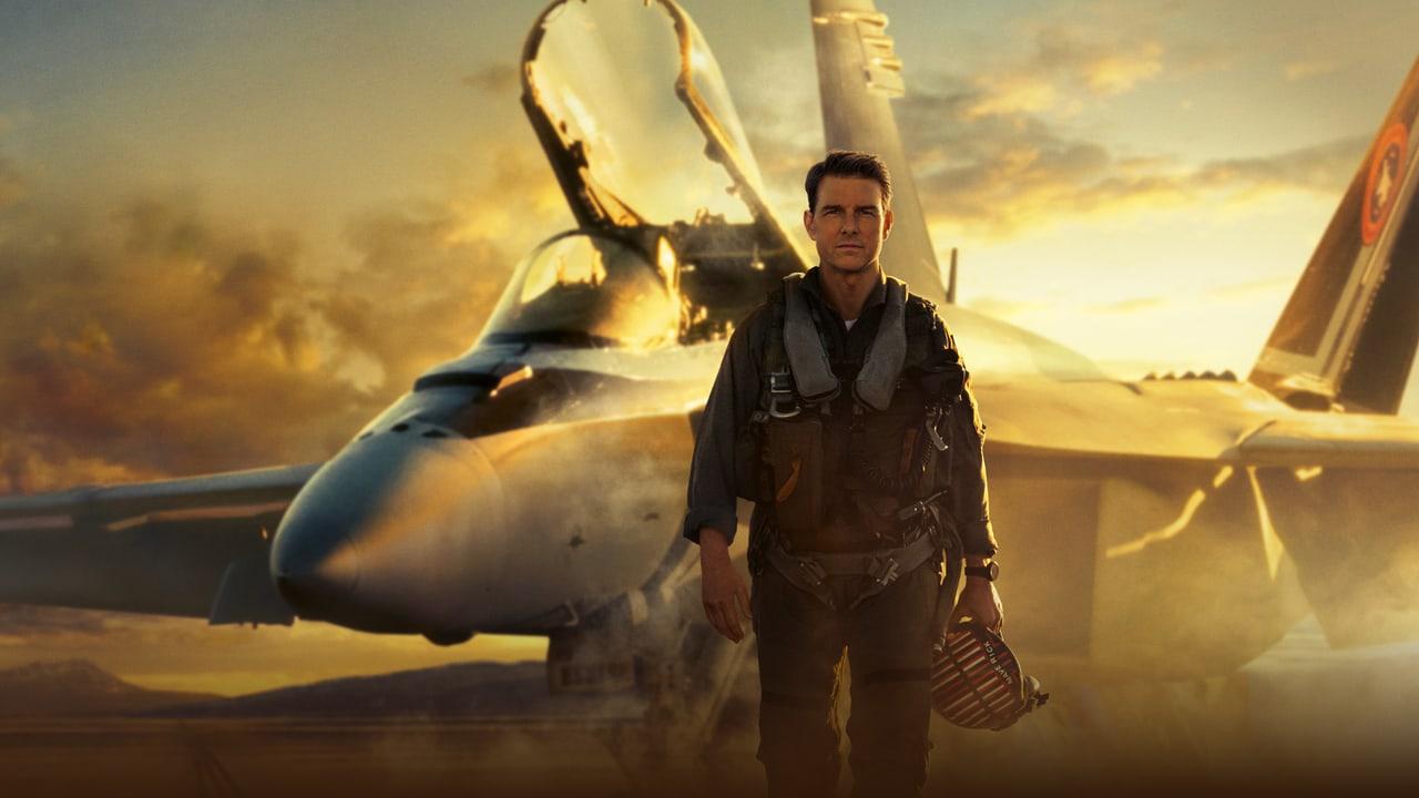 Maverick stands before a fighter jet in golden evening light. The wings and rear fuselage reach across the frame beneath layered sunset clouds.