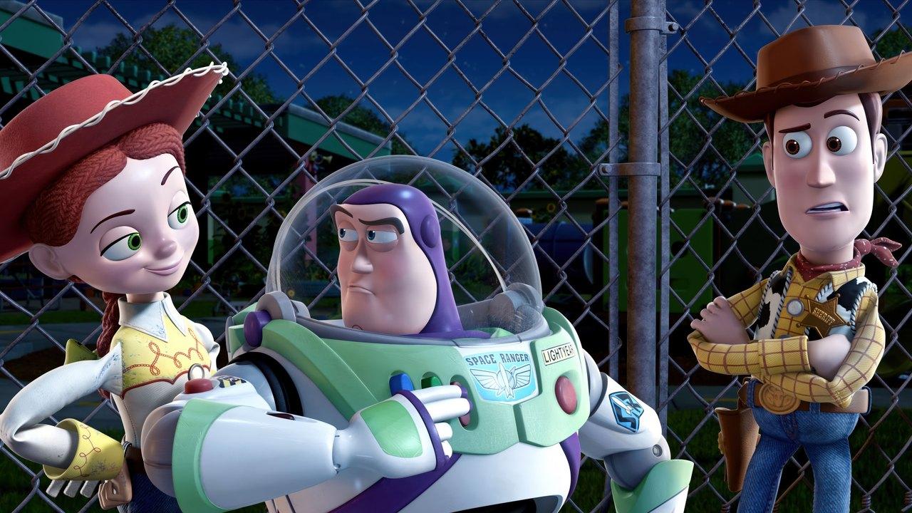 Jessie stands at the left and Woody at the right of Buzz against a blue night sky and wire fence.
