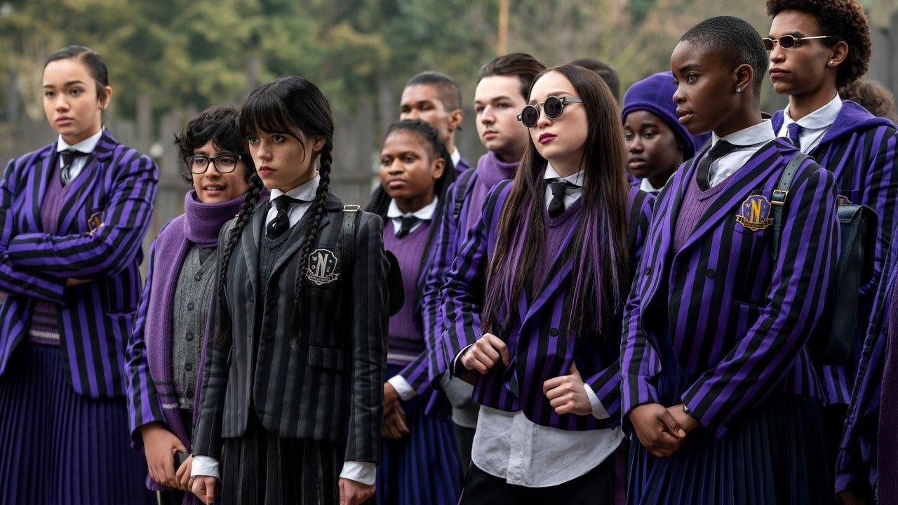 Wednesday and fellow Nevermore students stand outside in purple striped school uniforms.