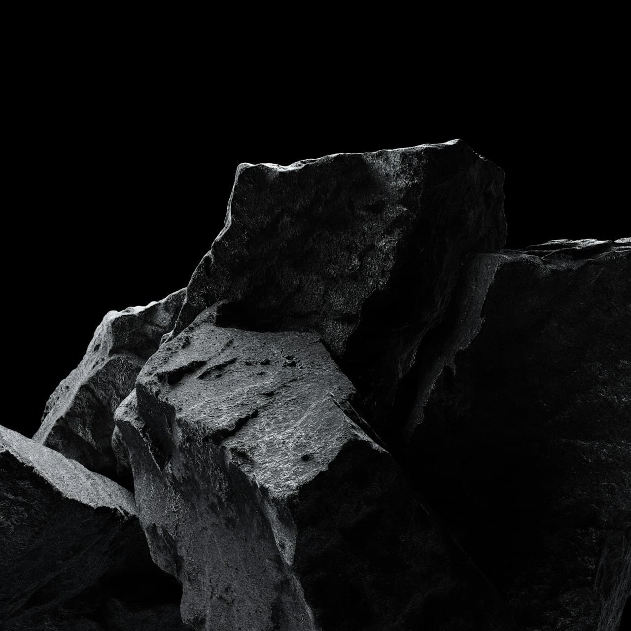 Black-and-white photograph of large, rough stones stacked in the lower portion of the frame. Dramatic lighting creates bright highlights on upper faces and heavy shadows in the gaps, carving strong contrast into the texture. A deep black background and empty upper area provide bold negative space, making the rocks feel isolated and sculptural. The composition is slightly off-center, letting angular forms and fractured surfaces dominate. Mood is austere, gritty, and tactile—ideal as a neutral texture backdrop.